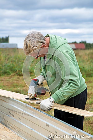 An adult man sawing boards electric jigsaw for building a house Stock Photo