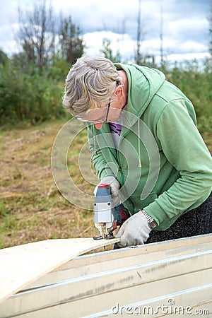 An adult man sawing boards electric jigsaw for building a house Stock Photo