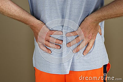 Adult Man Self Massaging His Low Back with Both Hands Through a Shirt Stock Photo