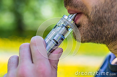 Adult man smoking a vape e-cigarette in the park Stock Photo