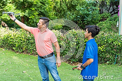 Adult man with son playing with drone in park Stock Photo