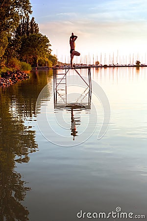 Adult man in yoga position on the pier Stock Photo