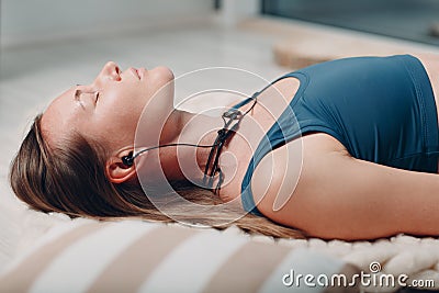 Adult mature woman doing yoga nidra and lay at home living room with online tutorials on laptop Stock Photo