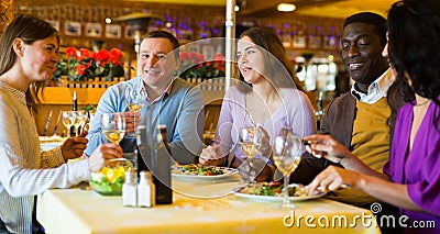 Adult men and women having friendly meeting at dinner in restaurant Stock Photo