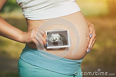 Adult pregnant woman holding a photo Medical ultrasound near the Stock Photo