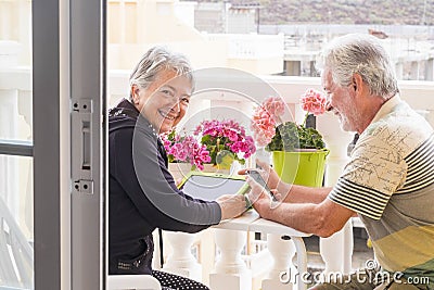 Adult senior couple use laptop outdoor leisure activity at the terrace at home. smile and enjoy the nice weather and the retired Stock Photo