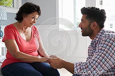 Adult Son Comforting Mother Suffering With Dementia Stock Photo