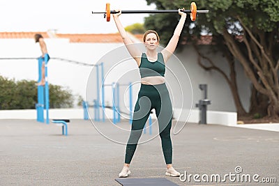 Adult sportive woman lifting a dumbbell outdoors Stock Photo