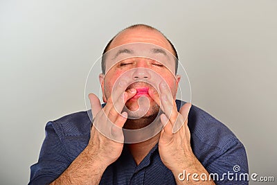 An adult and unshaven man in a blue shirt applies a mask of cream on his face, the concept of fashion, style and personal care Stock Photo