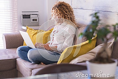 Adult woman at home in smart working with computer laptop sit down on the sofa writing and enjoying technlogy and communication Stock Photo