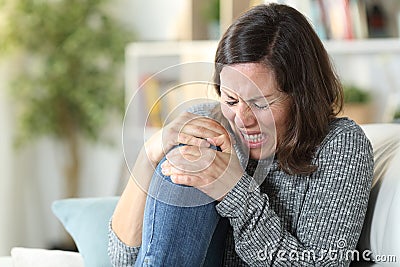 Adult woman in pain suffering knee ache at home Stock Photo
