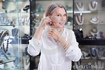Adult woman trying on a rose quartz necklace and earrings at a jewelry store Stock Photo