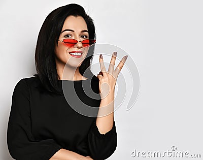Adult young woman. Black casual dress. Shows three fingers sign. White background and copy space. Stock Photo