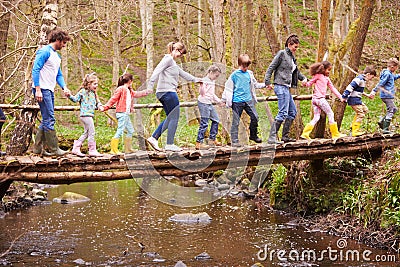 Adults With Children On Bridge At Outdoor Activity Centre Stock Photo