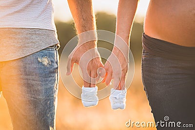 Adults holding baby pair of sneakers in white. Stock Photo