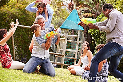 Adults and kids having fun with water pistols in a garden Stock Photo