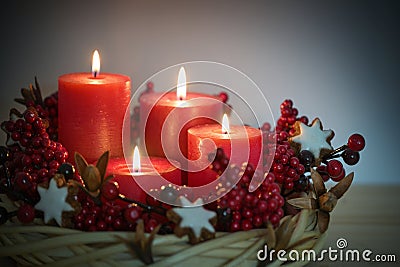 Advent wreath from willow wicker with four lighted red candles, cinnamon star cookies and berries, holiday decoration for Stock Photo