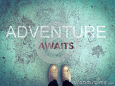 Adventure awaits word and feet wear white sneakers shoe on blue road Stock Photo