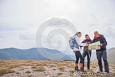 Adventure, travel, tourism, hike and people concept - group of smiling friends with backpacks and map outdoors Stock Photo