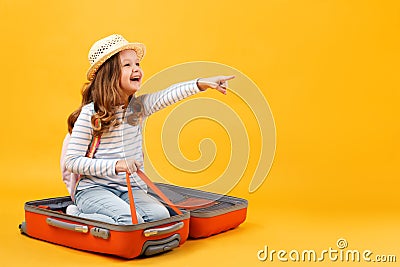 Adventure travel trip dream concept. A cheerful little girl sits inside a suitcase and shows her hand forward. Stock Photo