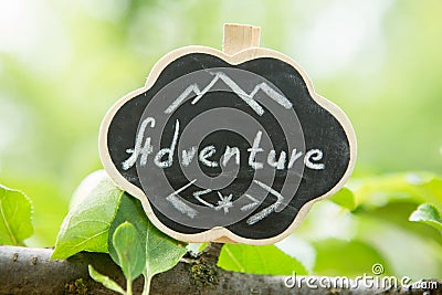 Adventure waiting for you concept - small sign with Adventure inscription outdoors, green blurred background Stock Photo
