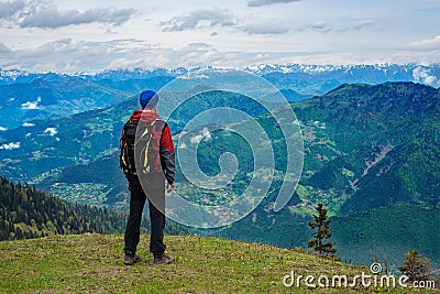 Adventurer with backpack stands on the green mountain meadow Stock Photo