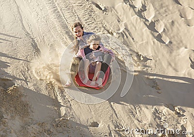 Adventuresome girls boarding down the Sand Dunes Stock Photo