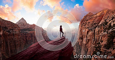 Adventurous Woman at the edge of a cliff is looking at a beautiful landscape view in the Canyon Stock Photo