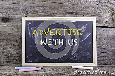 Advertise With Us. Chalk board on a wooden table Stock Photo