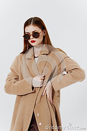 Advertising catalog shooting for the magazine. A red-haired stylish girl in a coat and glasses poses in the studio on a Stock Photo