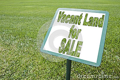 Advertising signboard with Vacant Land for Sale written on it against a green meadow - concept image Stock Photo