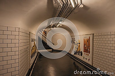 Advertising and stairs in passageway linking stations of the Paris Subway. Editorial Stock Photo