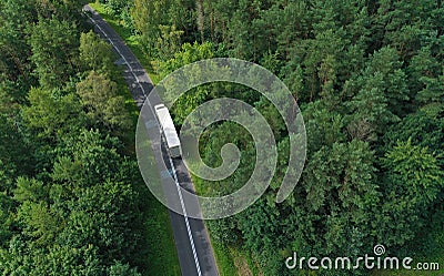 Aerial drone perspective view on white truck with cargo trailer riding through the forest on curved asphalt road Stock Photo