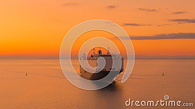 AERIAL: Drone view of a massive cargo carrier sailing across the sea at sunset. Stock Photo