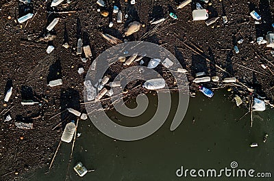 Aerial drone view waterfront scrap-heap plastic bottles rubbish pollution marine debris outdoors Stock Photo