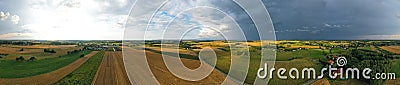 Aerial drone wide panoramic view on agricultural landscape with wheat field, village, meadows, forest and rain storm on horizon Stock Photo