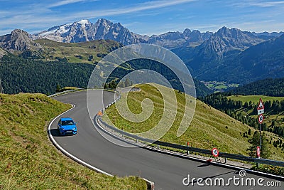 AERIAL: Flying above a cool blue sports car speeding up a scenic mountain road. Editorial Stock Photo