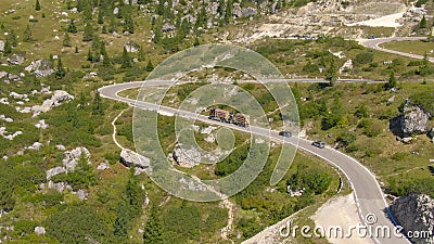 AERIAL: Flying along a steep mountain road in Dolomites and truck climbing it. Stock Photo