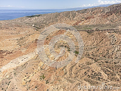 Aerial high angle view of the eroded landscape of Skazka Canyon in Kyrgyzstan with Lake Issyk-Kul in background Stock Photo