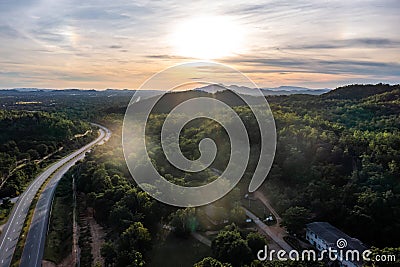 Aerial landscape of 4 lane road with residential area, forest, mountain, blue sky and sunlight with high angle view of main road Stock Photo