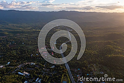 Aerial landscape of 4 lane road with residential area, forest, mountain, blue sky and sunlight with high angle view of main road Stock Photo