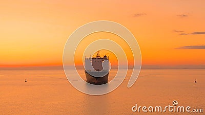 AERIAL: Large freight ship is transporting heavy cargo at gorgeous golden sunset Stock Photo