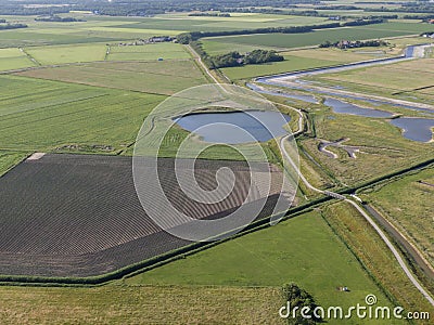 Aerial of meadowland with curving dike cycle lane and water storage on the dutch island of Texel Stock Photo