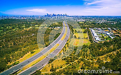 Aerial panorama of green parkland, Melbourne Polytechnic, and Melbourne CBD skyscrapers in the distance on summer day. Stock Photo