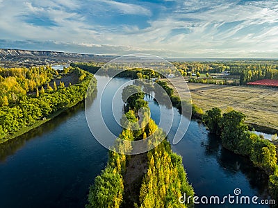 Aerial photography of a valley in autumn. The yellow color is observed in the vegetation, there is a large river divided in two. Stock Photo