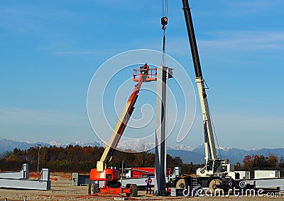 An aerial platform with a mobile crane install the first metal column of the new building Stock Photo