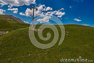 Aerial ropeway high in the mountains of Caucasus with grass plains and cow pastures in the background Stock Photo