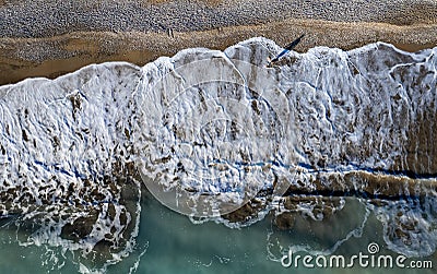 Aerial seascape of person walking in a beach. Stormy waves idyllic beach in winter. Stock Photo