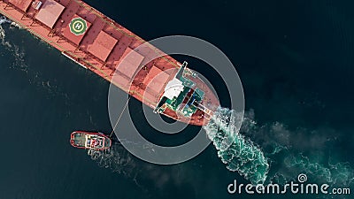 Aerial shot of a cargo ship approaching port with help of towing ship Stock Photo