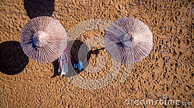 Aerial shot of a lone woman relaxing under an umbrella on the beach. Stock Photo